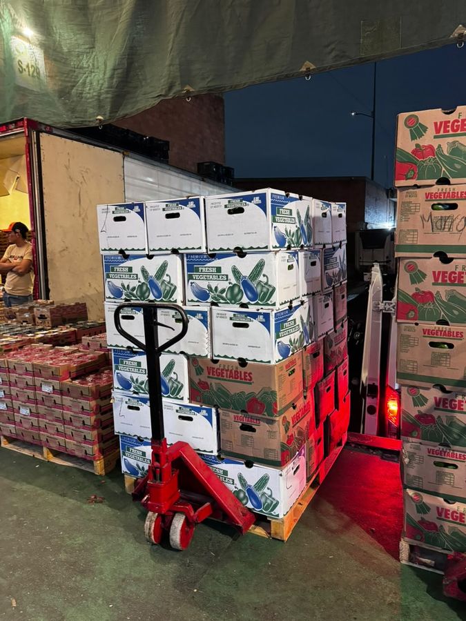 Tarima con cajas de verdura frente a un camión en la central de abasto, de madrugada